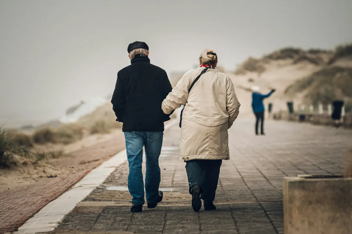 man in black jacket and blue denim jeans standing beside woman in beige coat during daytim