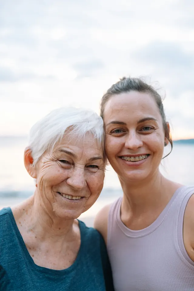 two women standing next to each other on a beach